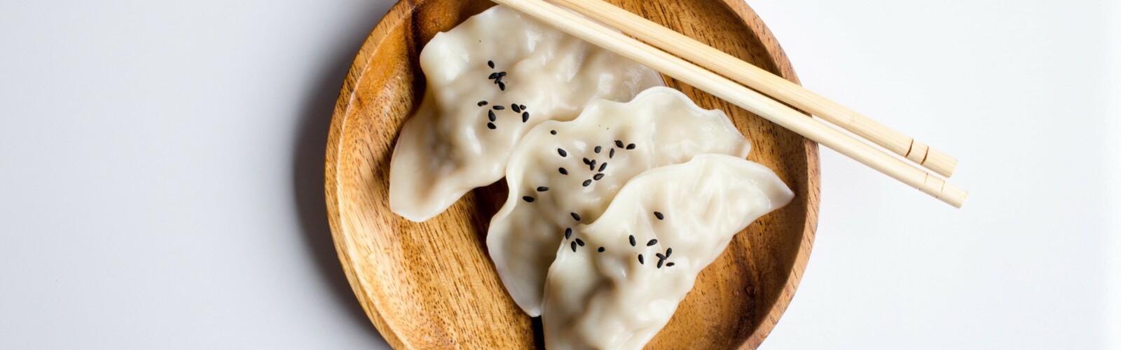 White dumplings on a bamboo plate, with chopsticks on the side